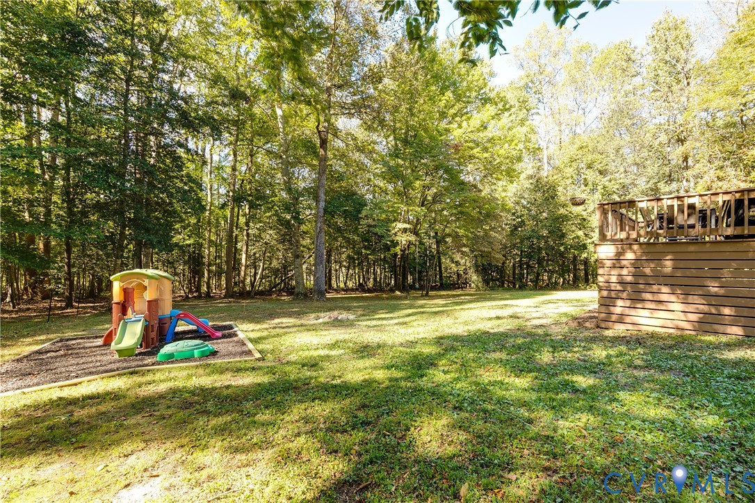 Expansive backyard featuring a natural treeline, mature trees, and a wooden deck