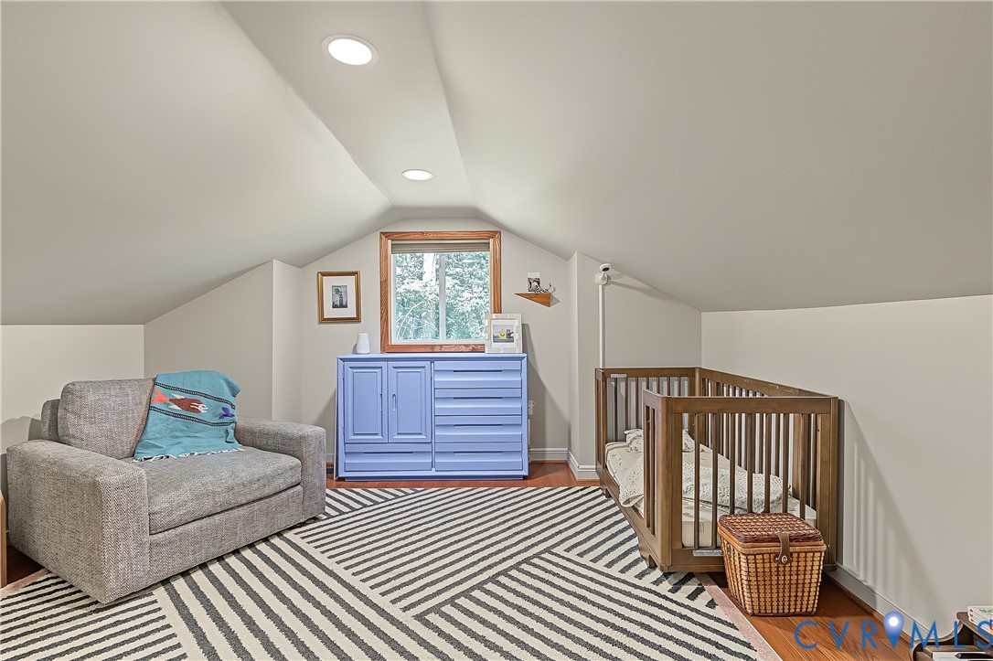 Sloped ceilings, recessed lighting, wood-finish flooring, and a window with wood trim