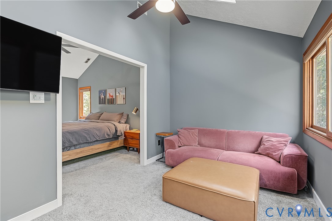 Vaulted ceilings, carpeting, dual-tone window trim, and a ceiling fan with integrated lighting
