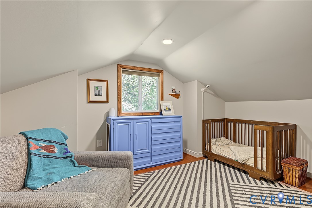 Vaulted ceiling with recessed lighting, wood-finish flooring, and built-in cabinetry