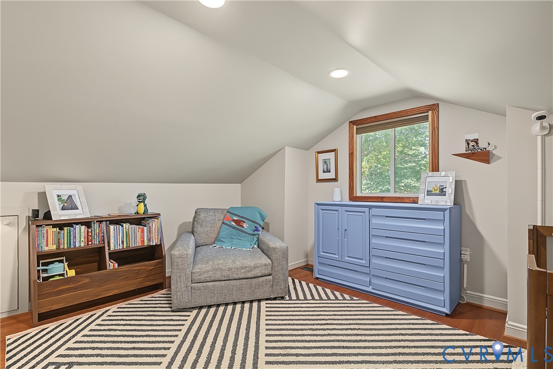 Sloped ceilings, wood-finish flooring, and a window with wood trim