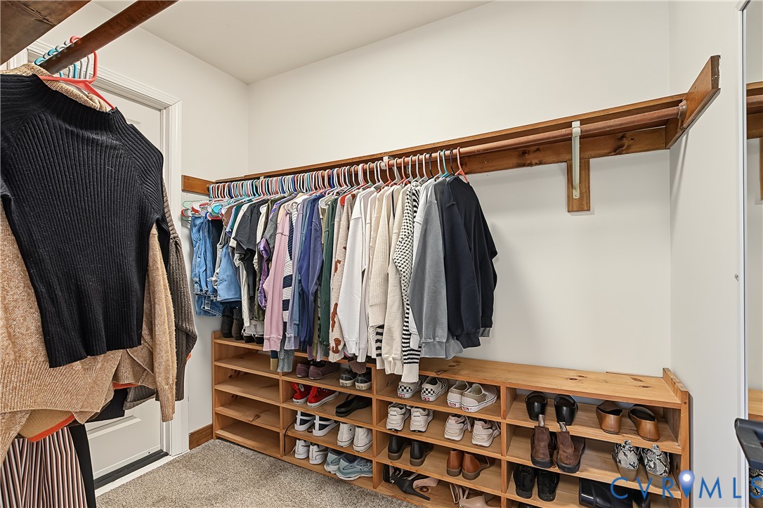 Walk-in closet featuring multi-tiered natural wood shelving and integrated rod storage