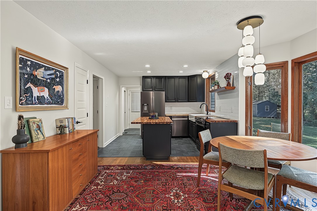 Kitchen featuring black cabinetry, butcher block countertops, apron-front sink, dark tile flooring, and a multi-globe pendant light fixture