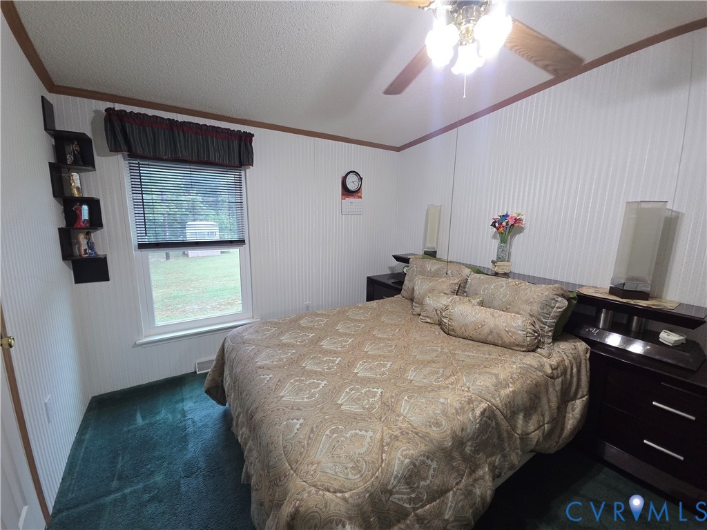 Vertical wood-paneled walls, carpeted flooring, and a ceiling fan with integrated light fixture
