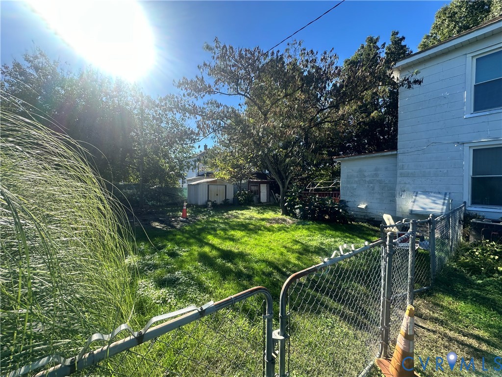 Rear exterior featuring a fenced yard, mature trees, and a detached storage structure