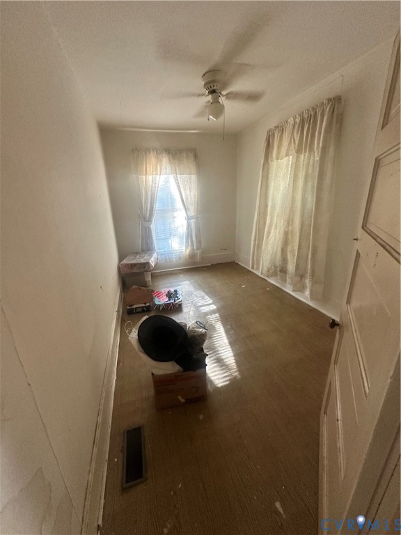 Room featuring two windows, neutral walls, wood-finish flooring, and a ceiling-mounted fan