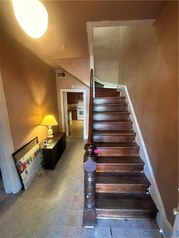 Staircase featuring dark-stained wood treads and an ornate wood-turned newel post