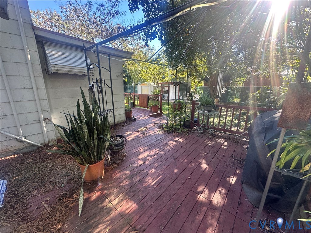 Exterior wood deck featuring a metal-frame pergola and wood-slat railing