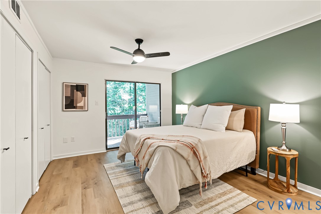 Wood-finish flooring, accent wall, ceiling fan with integrated lighting, dual-panel closet doors, and sliding glass door