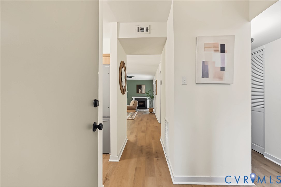 Entryway featuring wood-finish flooring, white walls, and a louvered-panel closet door