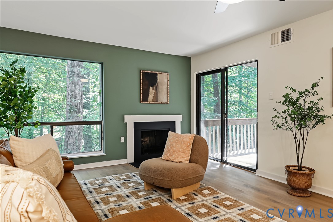 Living area featuring a fireplace with a minimalist mantel, expansive picture windows, wood-finish flooring, and sliding glass doors