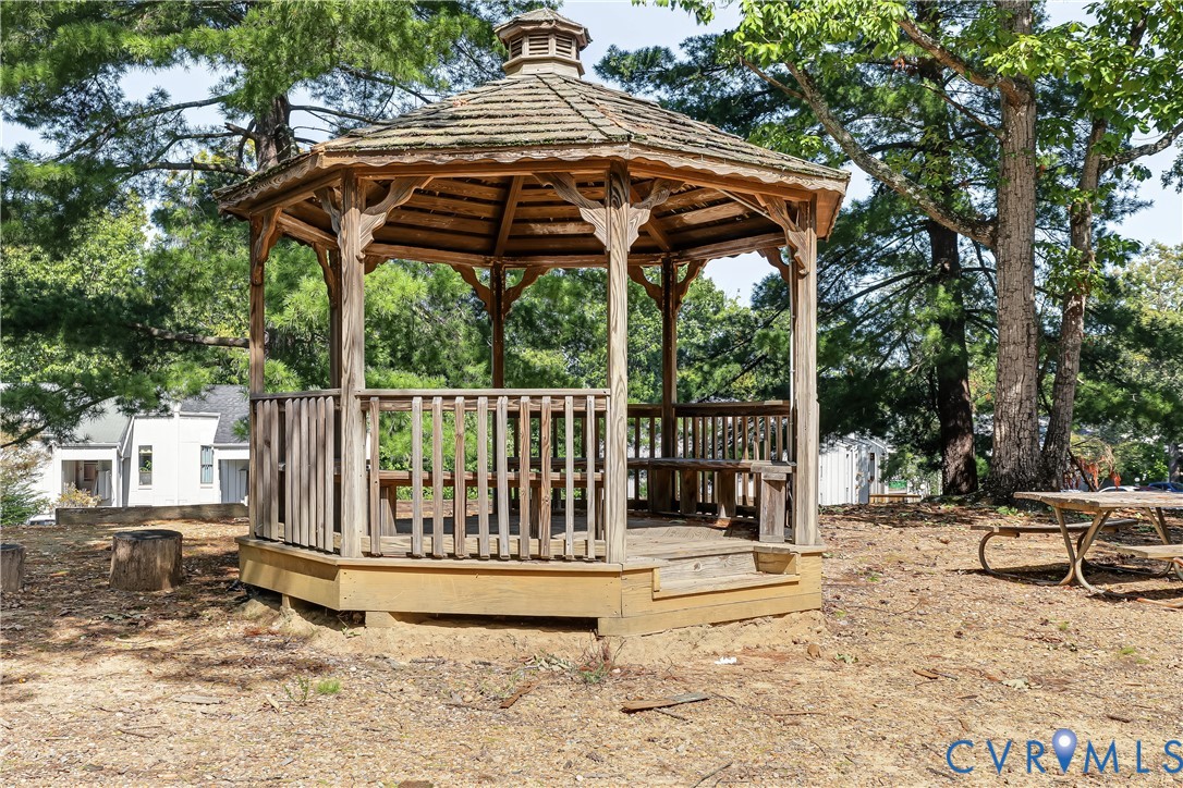 Wooden octagonal gazebo featuring shingle roofing, decorative wood brackets, and built-in perimeter bench seating