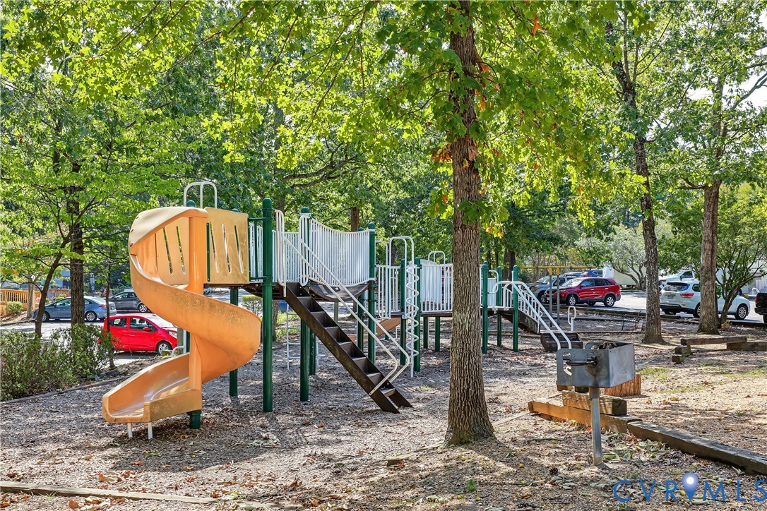 Recreational area featuring a spiral slide, climbing structure, metal stairs, and a built-in charcoal grill