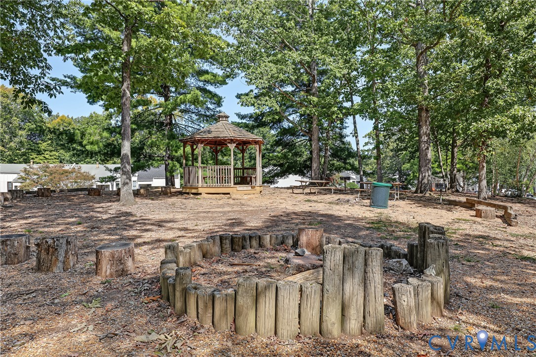 Wooded lot featuring an octagonal gazebo, a circular log-retained fire pit, and mature trees