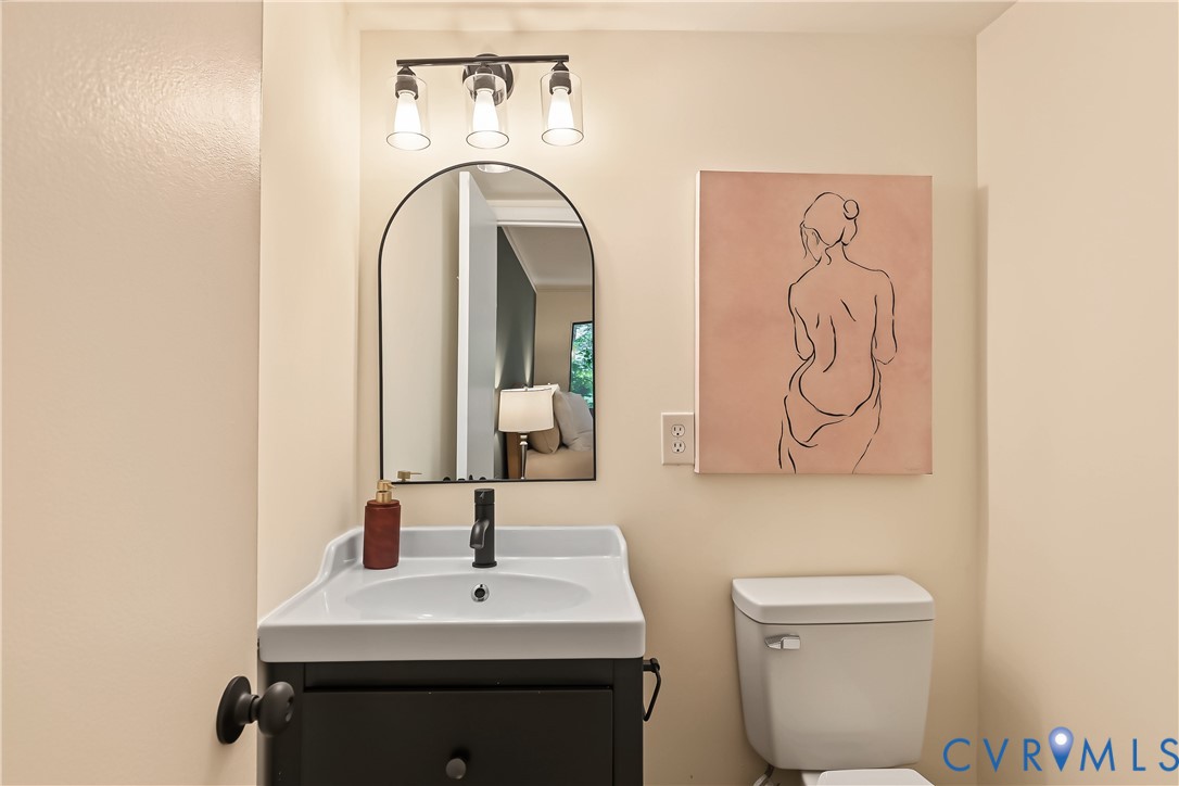 Wall-mounted vanity featuring a porcelain basin, arched mirror with black frame, three-light fixture with clear glass shades, and matte black single-handle faucet