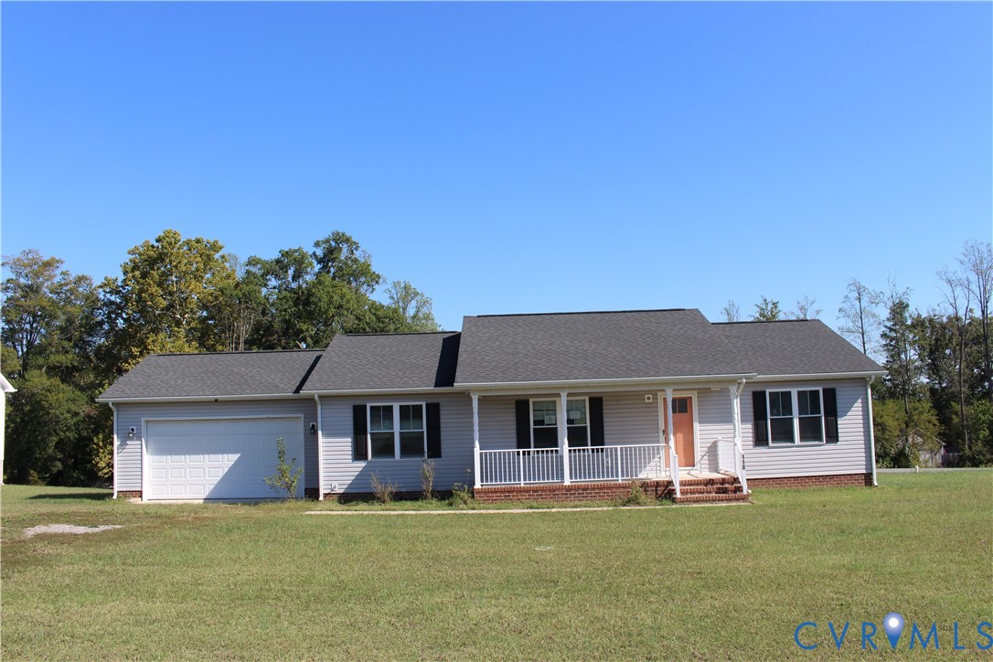Single-story residence featuring light gray siding, a brick foundation, a covered front porch with white railing, and an attached two-car garage Single-story residence featuring light gray siding, a brick foundation, a covered front porch with white railing, and an attached two-car garage