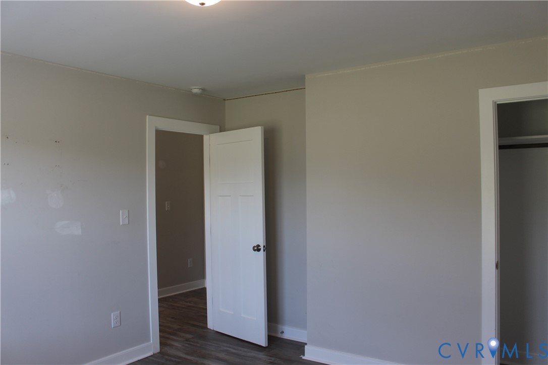 Neutral-toned interior space featuring three-panel shaker-style interior doors, overhead flush-mount lighting, and wood-finish flooring
