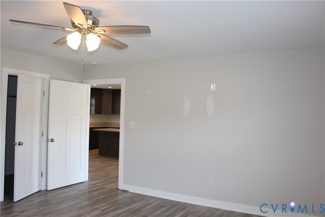 Interior space featuring wood-finish flooring, a ceiling fan with integrated lighting, and white shaker-style panel doors