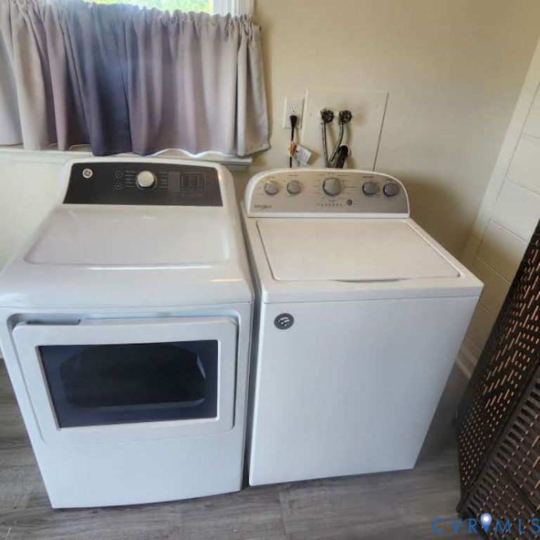 Dedicated laundry area featuring a top-load washer and front-load dryer with wood-finish flooring