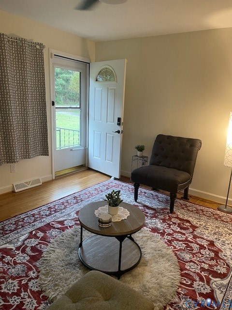 Wood-finish flooring, white paneled entry door with arched decorative glass insert, and exterior screen door