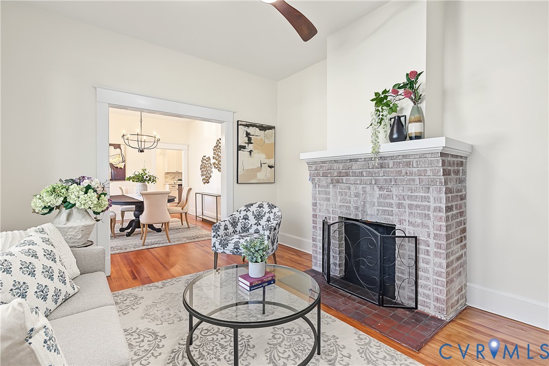 Living area featuring a floor-to-ceiling brick fireplace with a custom mantle, wood-finish flooring, and crown molding
