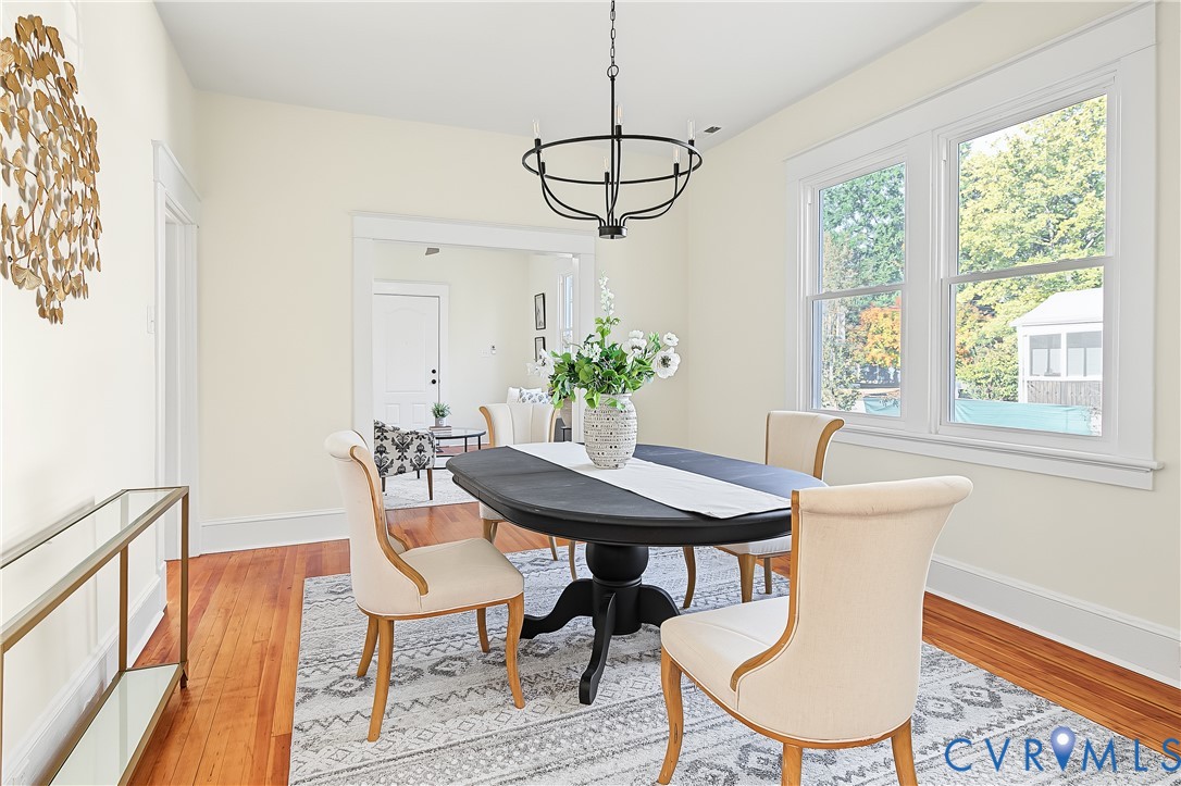 Hardwood flooring, double-hung windows with wide casing, and a matte black chandelier