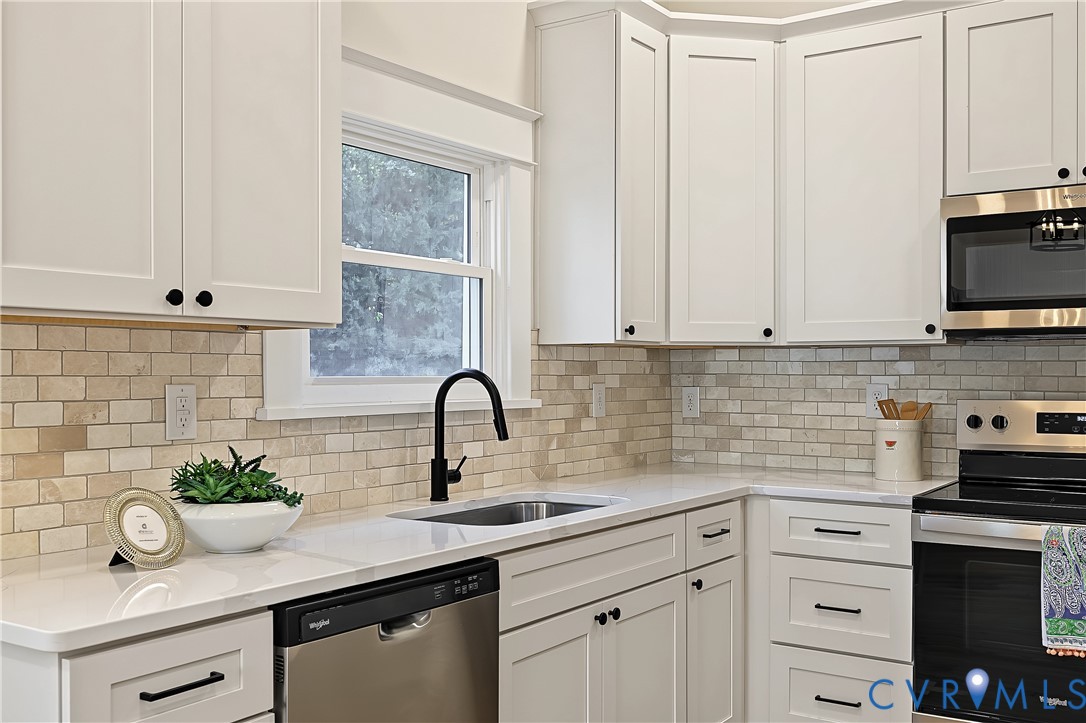 Kitchen featuring white shaker-style cabinetry, white solid-surface countertops, a stone tile backsplash, a stainless steel dishwasher, and a matte black gooseneck faucet