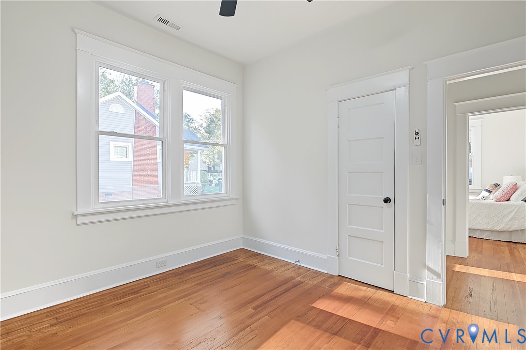 Room featuring wood-finish flooring, multi-pane windows, and five-panel interior door with white casing and trim