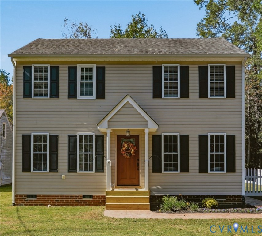 Two-story residence featuring horizontal lap siding, a gable-roofed front entry porch, multi-pane windows with shutters, and a brick-veneer foundation base