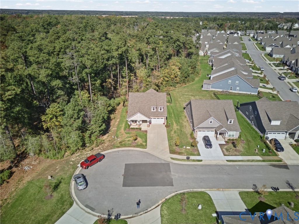 Cul-de-sac location featuring a multi-gabled roofline, concrete driveway, attached garage, and a lot perimeter bordering mature wooded greenspace