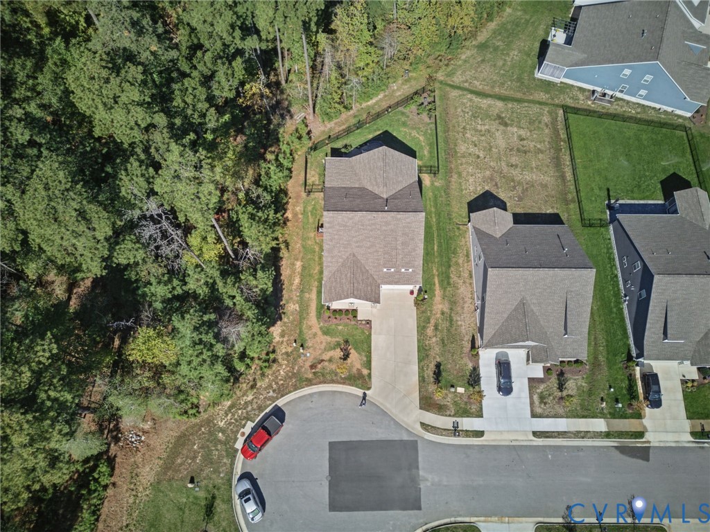 Aerial perspective featuring a lot situated at the end of a cul-de-sac, asphalt driveway, asphalt shingle roofing, and established perimeter tree line