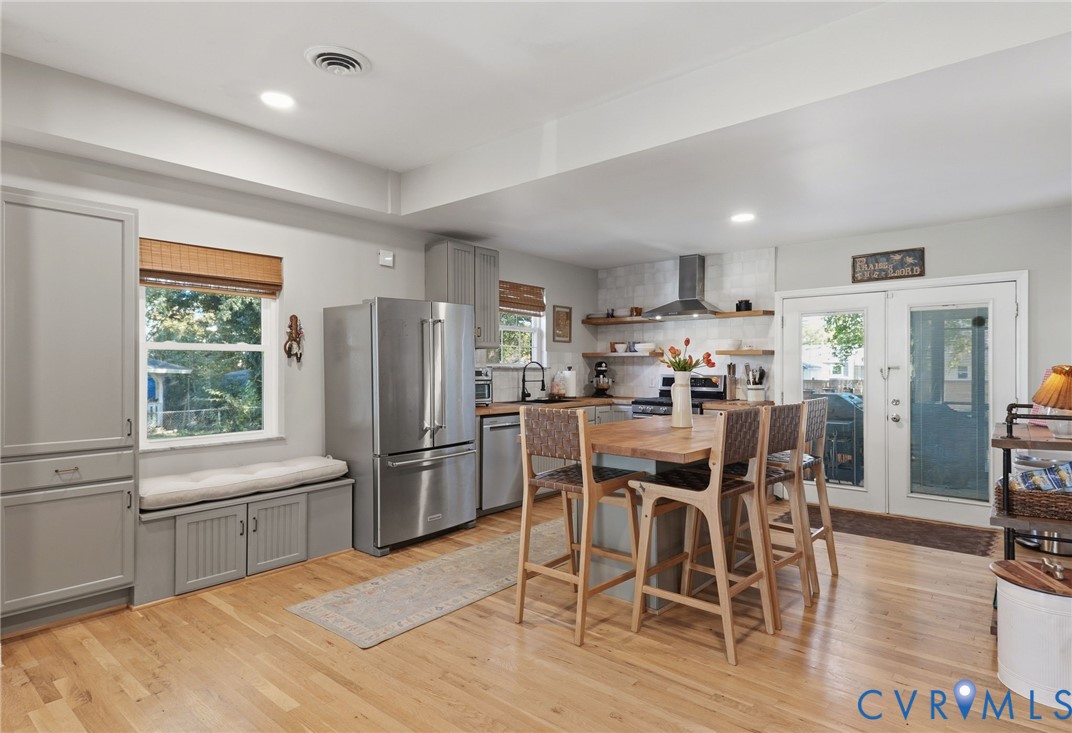 Kitchen featuring wood-finish flooring, stainless steel appliances, a central island with a wood countertop, built-in cabinetry, and open shelving