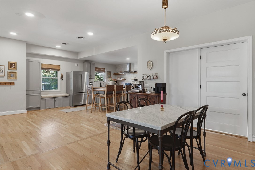 Kitchen featuring wood-finish flooring, recessed lighting, stainless steel refrigerator, built-in cabinetry, and a decorative overhead pendant light