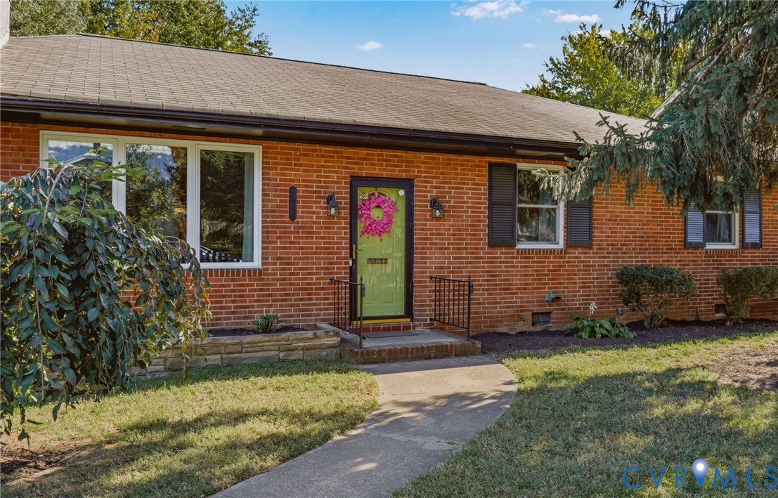 Red brick exterior featuring dark shutter accents, multi-pane windows, and a stone-masonry planter bed