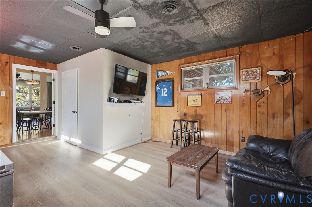 Wood-panelled wall cladding, wood-finish flooring, dark-toned drop ceiling, and an integrated ceiling fan with light fixture