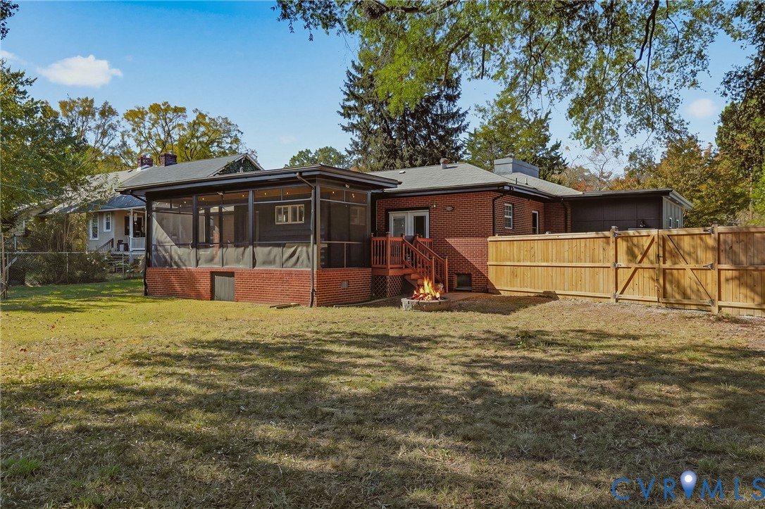 Exterior featuring a red brick facade, an enclosed screened porch, a wood deck with stairs, and a privacy fence