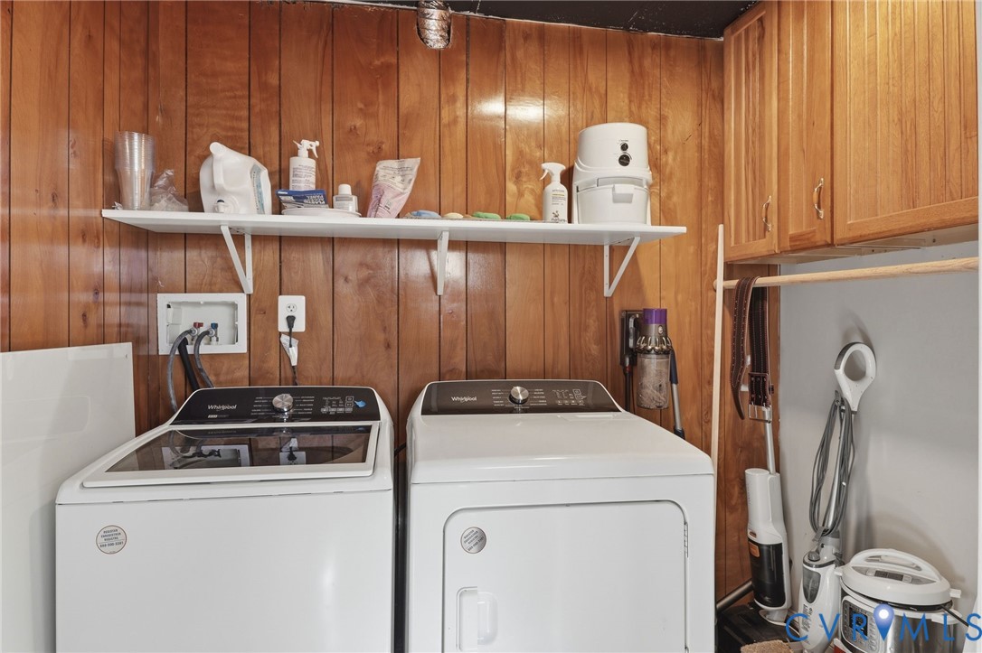 Laundry space featuring wood-paneled walls, wall-mounted cabinetry, and a tiered open shelving unit