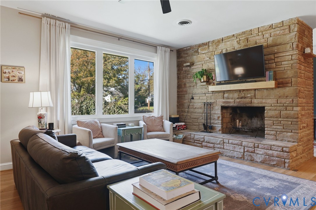 Floor-to-ceiling stone fireplace featuring a stone hearth and a natural wood mantel