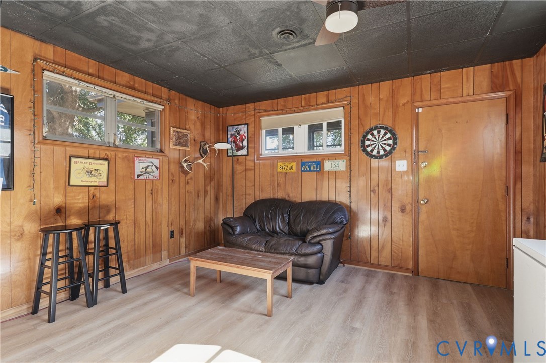 Wood-paneled wall surfaces, light wood-finish flooring, and a textured black ceiling featuring a flush-mount light fixture