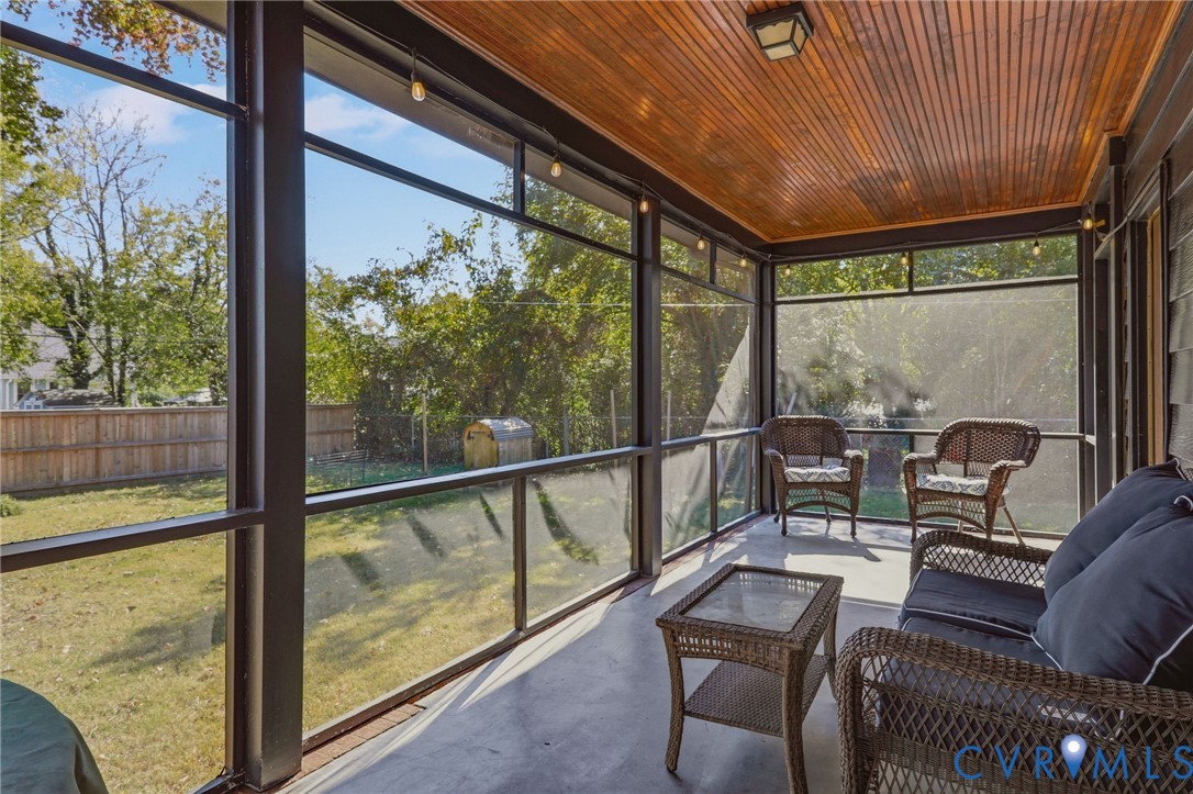 Screened-in porch featuring a natural wood-plank ceiling, structural metal framing, and a concrete floor