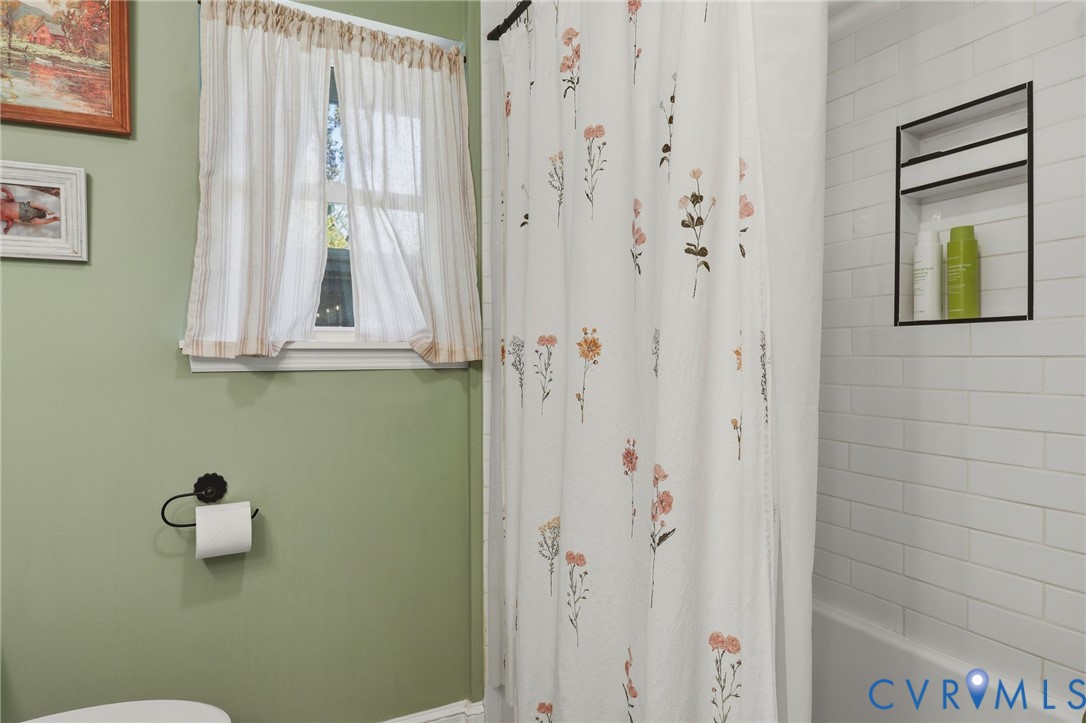 Bathroom featuring white subway tile wall surround, built-in recessed shower niche with black trim, and a window with a dedicated sill