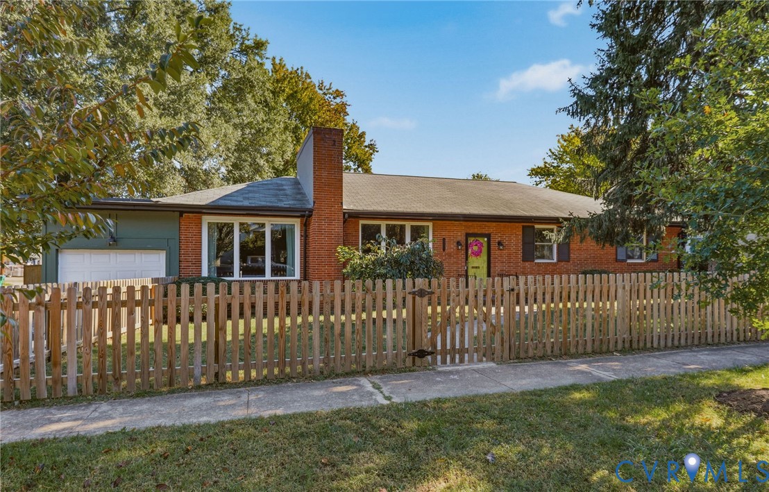 Single-story exterior featuring a brick facade, exterior chimney, wooden picket fence, attached garage, and multi-pane windows Single-story exterior featuring a brick facade, exterior chimney, wooden picket fence, attached garage, and multi-pane windows