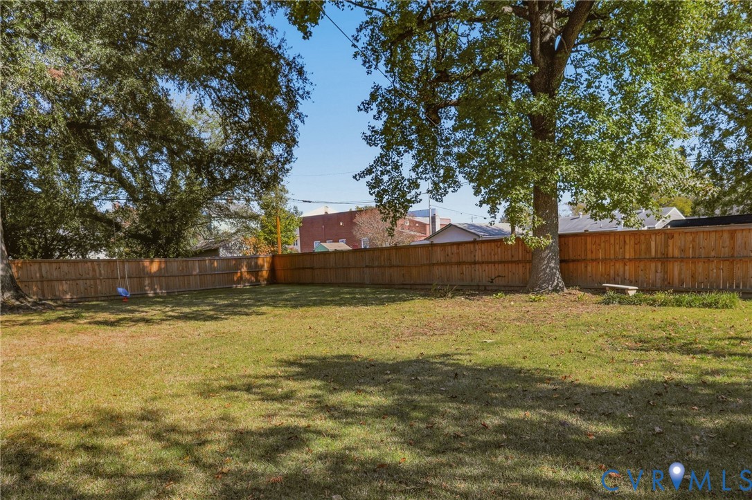 Expansive backyard featuring a fenced perimeter, mature trees, and a level grass lawn