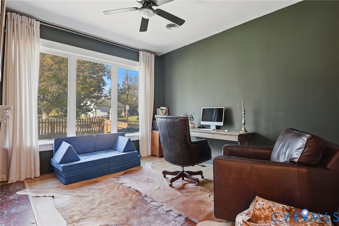 Large picture window with natural light, wood-finish flooring, ceiling fan, and painted accent wall