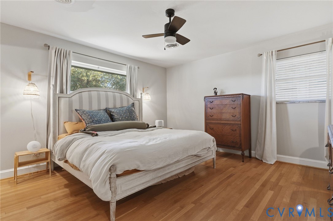 Wood-finish flooring, central ceiling fan with integrated lighting, and dual wall-mounted light fixtures