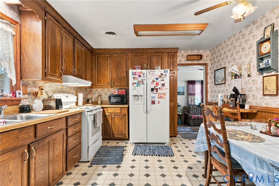 Kitchen featuring wood cabinetry, laminate countertops, a dual-basin stainless steel sink, built-in recessed ceiling lighting, and tile flooring