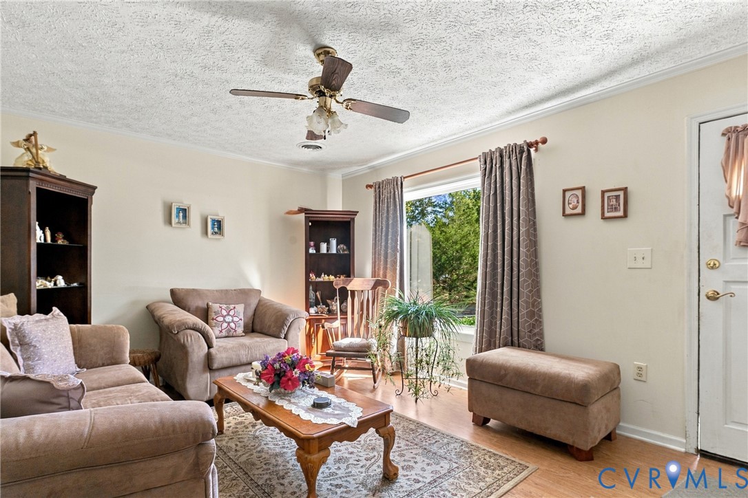 Neutral-toned walls, wood-finish flooring, ceiling fan with integrated lighting, and a large window providing natural illumination