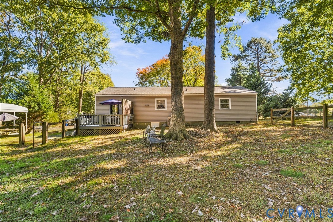 Exterior featuring horizontal siding, a wooden deck, and a post-and-rail fence set within a partially wooded lot