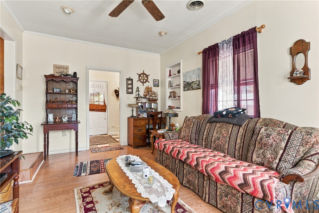 Living area featuring wood-finish flooring, ceiling fan, recessed lighting, and built-in wall shelving