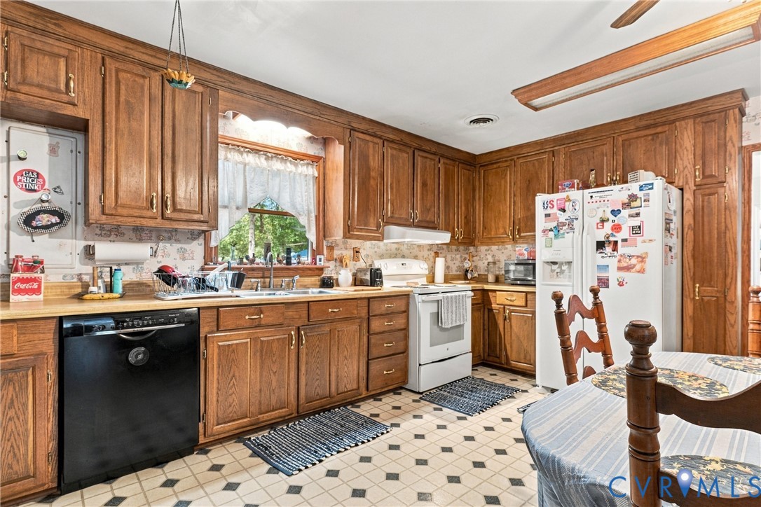 Kitchen featuring extensive wood cabinetry, solid surface countertops, and a double-basin stainless steel sink